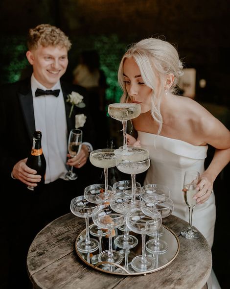 bride sipping from champagne tower decoration with groom rock my wedding the kensington photographer
