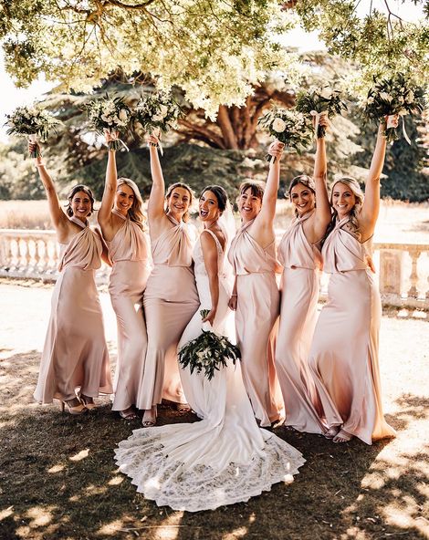The bride wears a Blue by Enzoani wedding dress with the bridesmaids in blush satin dresses.