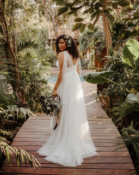 Tulum destination wedding with tropical plants a bride in a floaty dress with naturally curly hair 