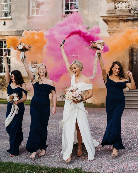 Bride and bridesmaids in navy blue dresses take part in smoke bomb photoshoot for wedding