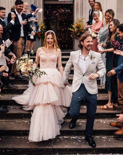 Bride in blush pink wedding dress descends the steps of Old Marylebone Town Hall with groom