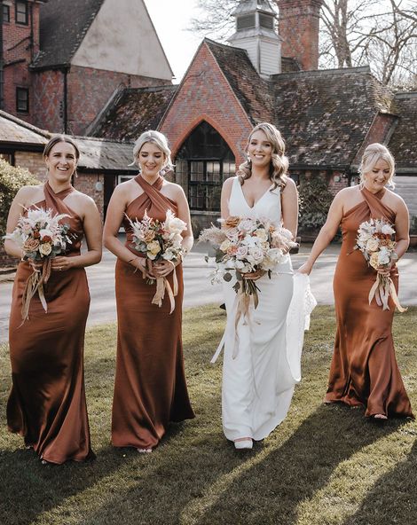 Bride walks with her bridesmaids in stunning satin halter neck copper bridesmaid dresses. 