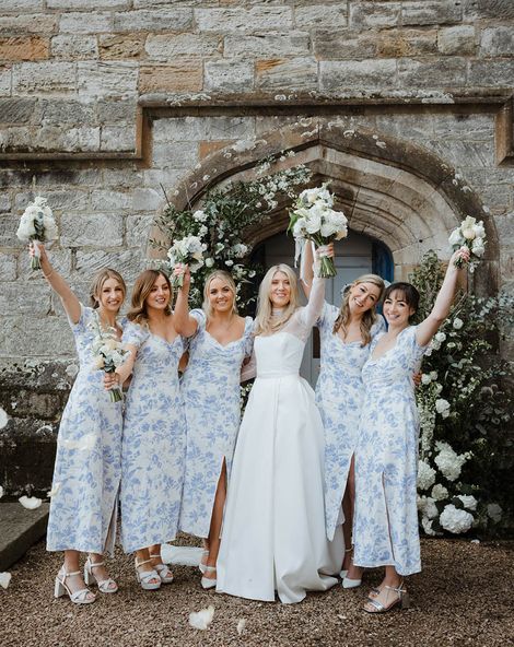 Bride with bridesmaids in blue patterned dresses at their wedding venue.