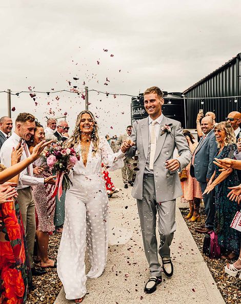 fun east quay Whitstable wedding with bride in a jumpsuit, pink & red colour scheme and mismatched bridesmaid dresses