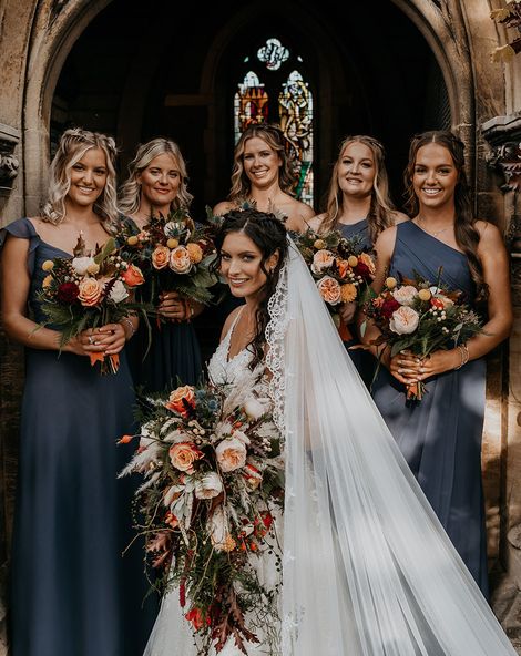 Bride holding cascade wedding bouquet with bridesmaids in navy blue dresses