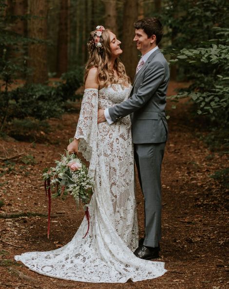 Bride in strapless lace medieval wedding dress with custom sleeves with groom in woodland after handfasting ceremony. 