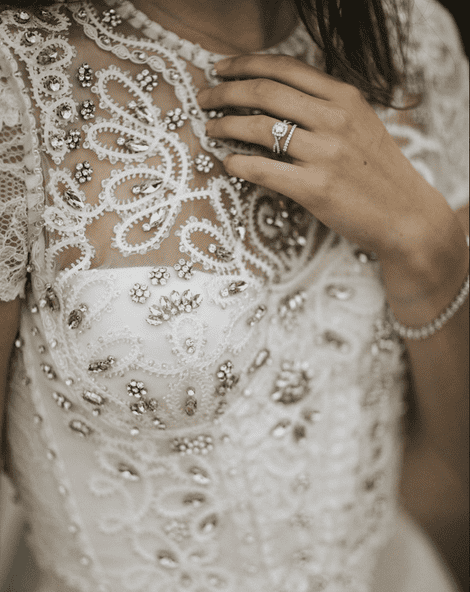 Bride in a bejewelled wedding dress wearing a sparkly engagement and wedding ring.