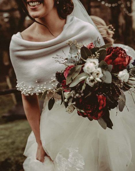 Winter wedding with bride in a tulle wedding dress and wool coverup holding a red rose bridal bouquet 