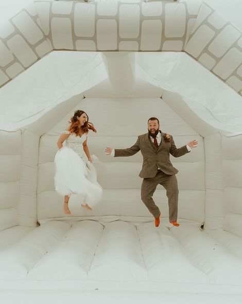 Bouncy castle wedding with bride and groom jumping on the white bouncy castle.