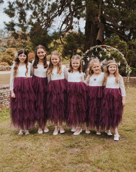Six flower girls in purple tulle layered flower girl dresses with lace top detail