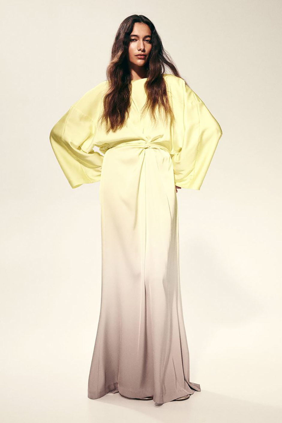 Floor length gown with twist detail at the waist and draped long sleeves in yellow from h&m as summer wedding guest dress idea
