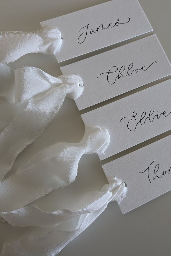 Beautiful off-white modern calligraphy place cards, finished with a delicate silk ribbon