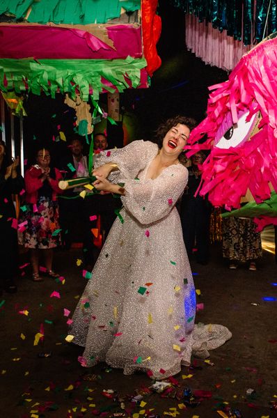 Bride smashing bright coloured pinatas with confetti flying out