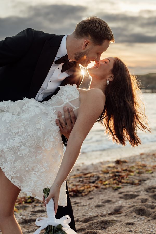 A bride and groom share a kiss as the sun sets behind them in Devon. 