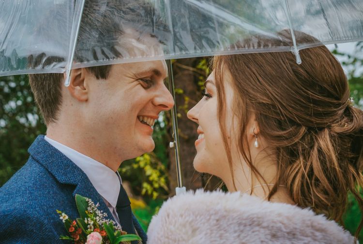 david lefebvre photography close up photo of bride and groom in navy tweed suit and shawl under clear umbrella at countryside wedding in buckinghamshire uk with david lefebvre photography