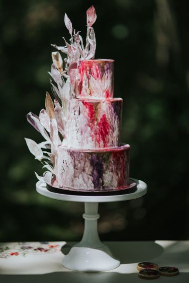 cherry tree cakerie bold watercolour wedding cake with wafer paper leaves on dresser