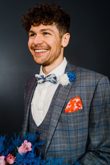 Blue and grey check suit with bow tie for Blue and red wedding bouquet for colourful wedding theme