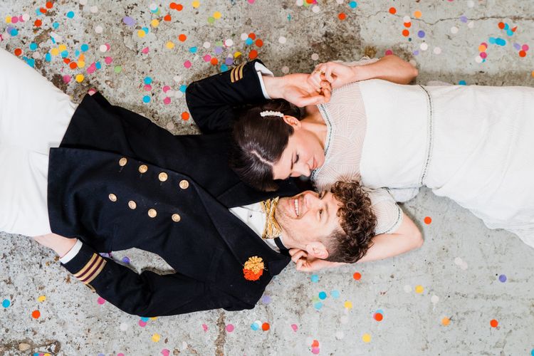 Bride and groom laying on the floor of Boat shed for colourful wedding theme