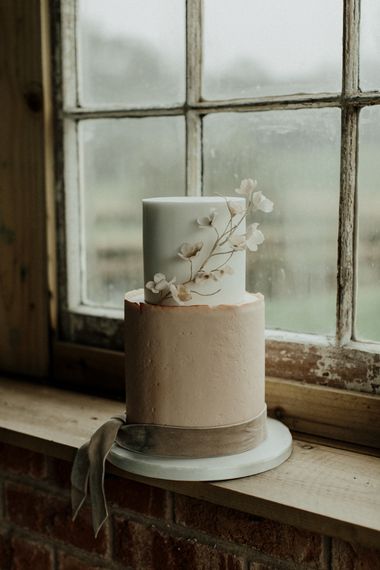 Pink and white wedding cake with delicate flower decor and velvet ribbon