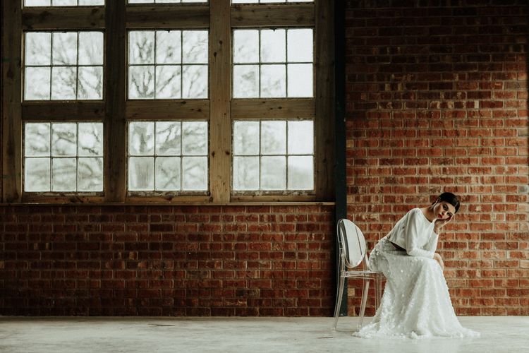 Bride in bridal crop top and sequin skirt sitting on a Ghost chair