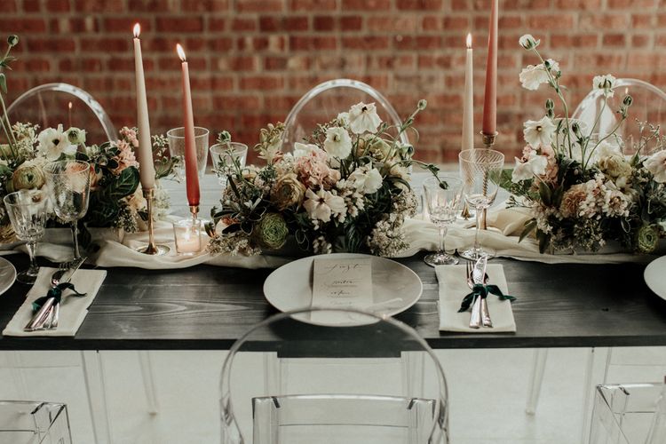 Elegant wedding table decor with ghost chairs, flower centrepieces and taper candles