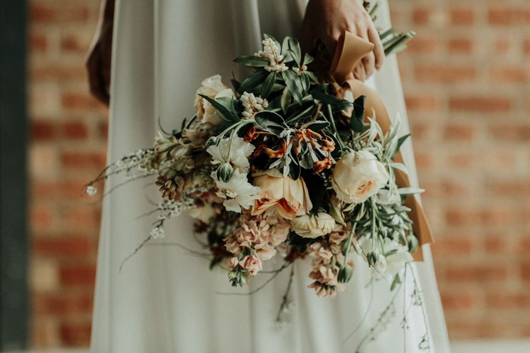Muted flower wedding bouquet tied with ribbon and bridal crop top