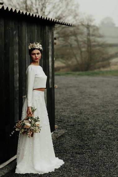 Stylish bride in sequin skirt and bridal crop top with flower crown and bouquet