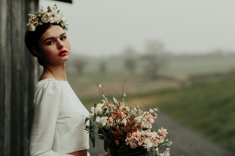 Beautiful bride with red lipstick holding an earthy bouquet in a bridal crop top