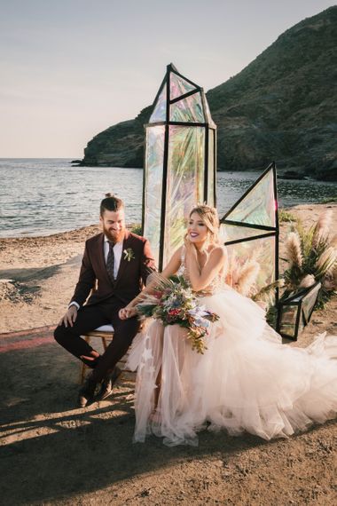 Bride and groom sat on beach