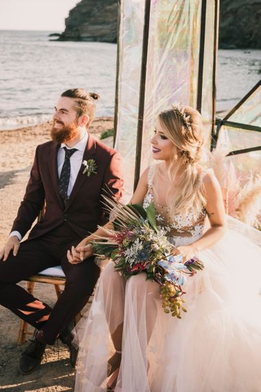 Bride and groom sat on beach