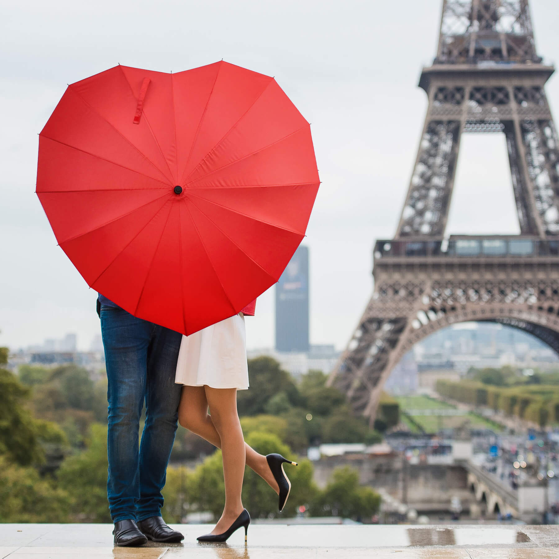 couple-behind-red-heart-shaped-umbrella-eiffel-tower-paris.jpg