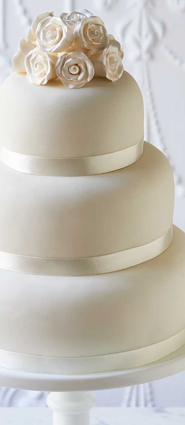 classic white three tier wedding cake for at-home decoration with roses on the top